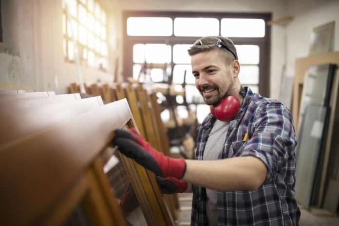 Carpenter checking quality of his work in carpentry workshop.
