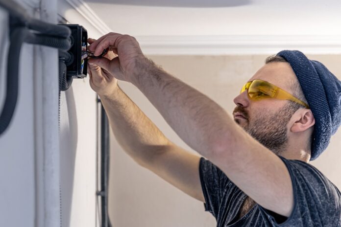 An Electrician is Mounting Electric Sockets on The White Wall Indoors