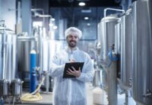 The Importance of Oil Removal in Food Processing Technology Food processing plant interior with positive smiling technologist holding checklist.