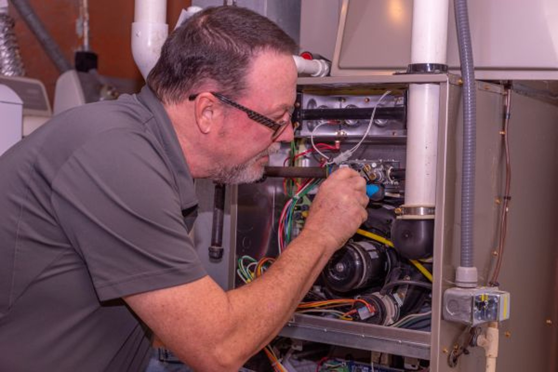 What Maintenance Services Should Be Done on an HVAC in Fall? HVAC repair specialist repairing an HVAC machine