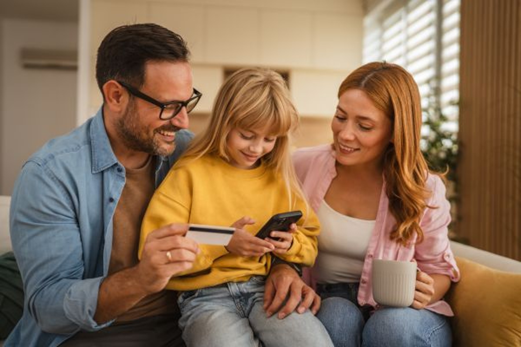 Why Your Child Needs a Bank Account: Building Financial Literacy A girl using mobile banking with her parents